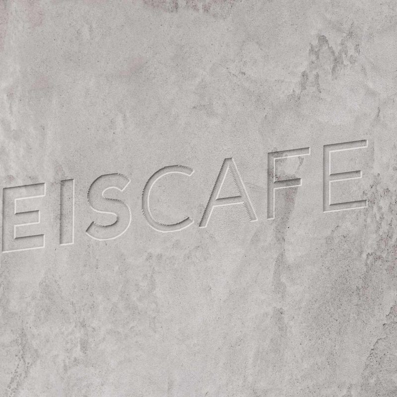Brand refresh for Eis Cafe by Crate47 showing the updated logo design debossed on a concrete wall in the interior design
